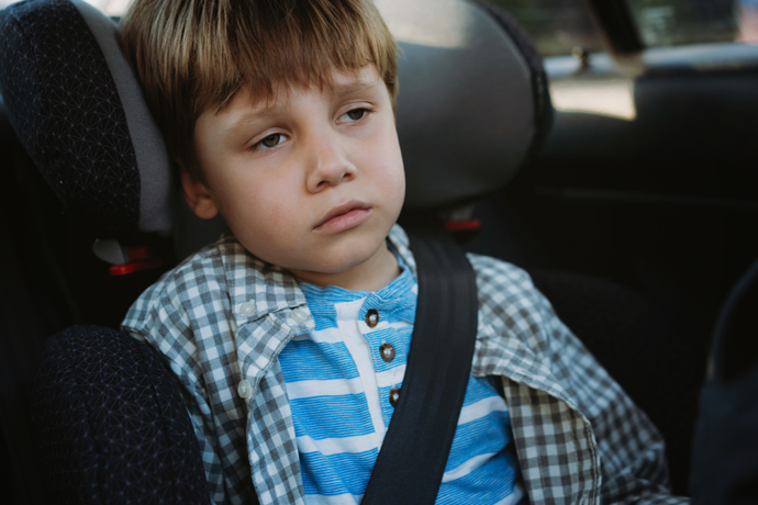 Niño mareado en el asiento trasero del carro