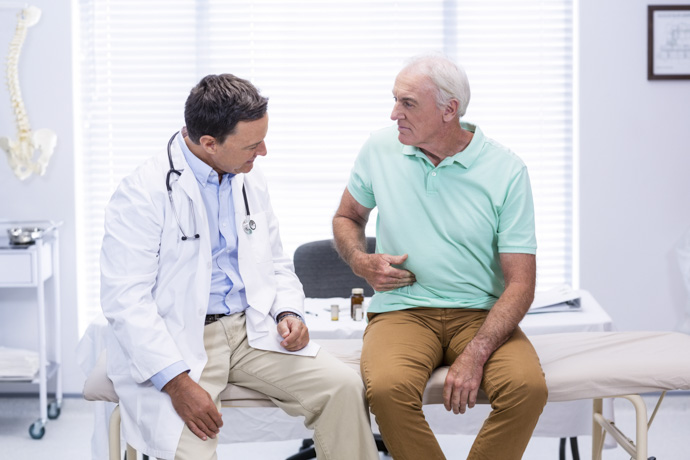 Médico diagnosticando la causa del dolor en la boca del estómago a paciente. 