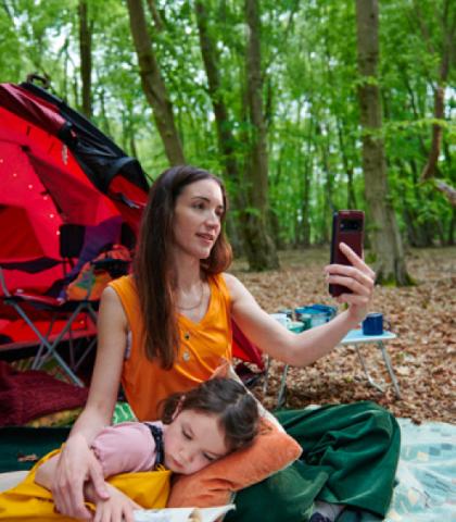 Mujer en una zona de camping buscando señal en su celular.
